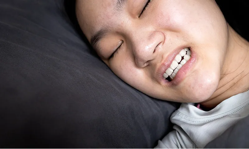 Person grinding teeth while sleeping due to stress and poor sleep