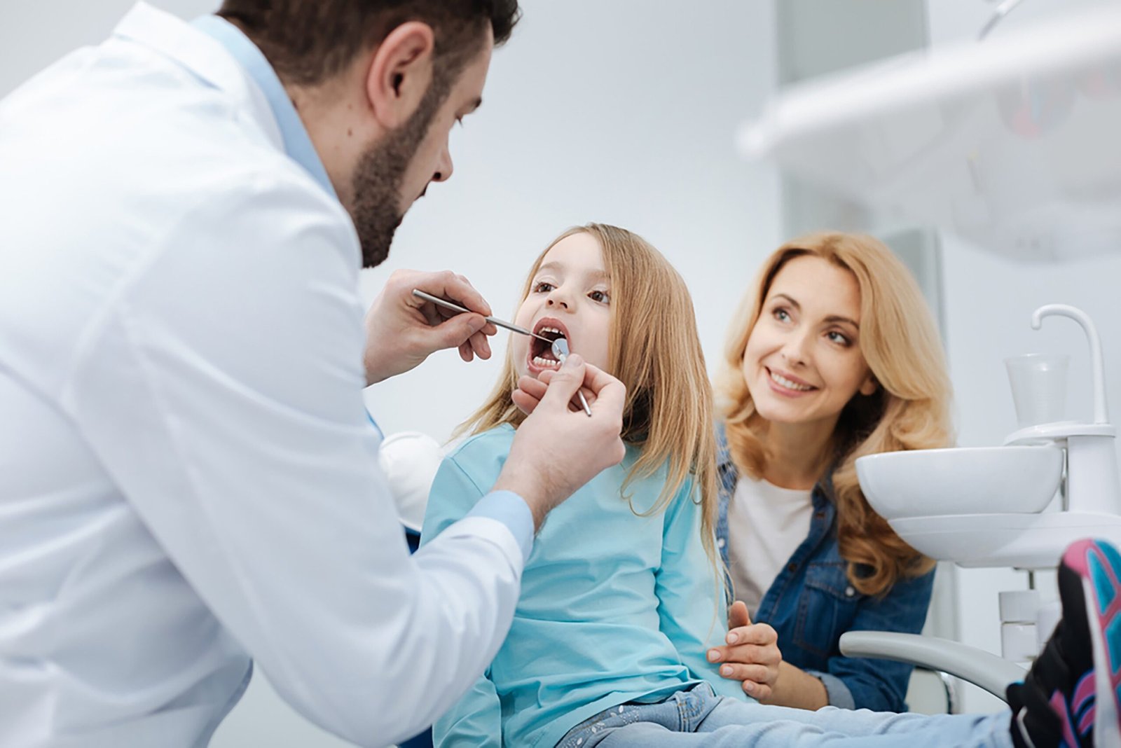Dentist explaining teeth grinding to parent and child during check-up.”